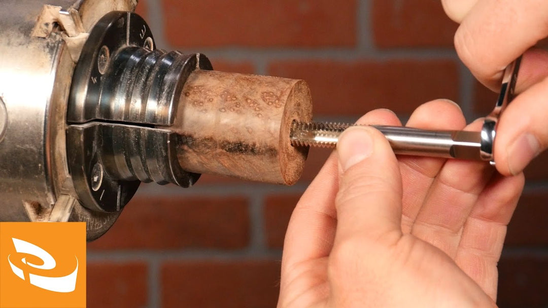 Cutting threads in a wood blank with a threading tap.
