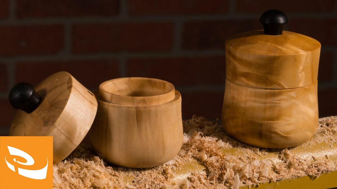Two wooden salt canisters on a lathe bed.
