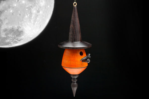 A turned bat house ornament with orange body and black hat and finial.