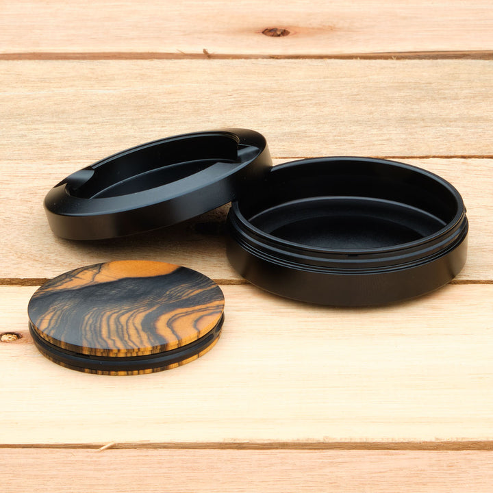 Black aluminum pouch case with turned lid on a wooden surface