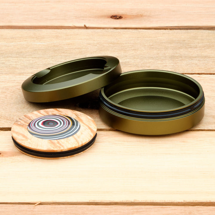 Green aluminum pouch case with turned lid on a wooden surface