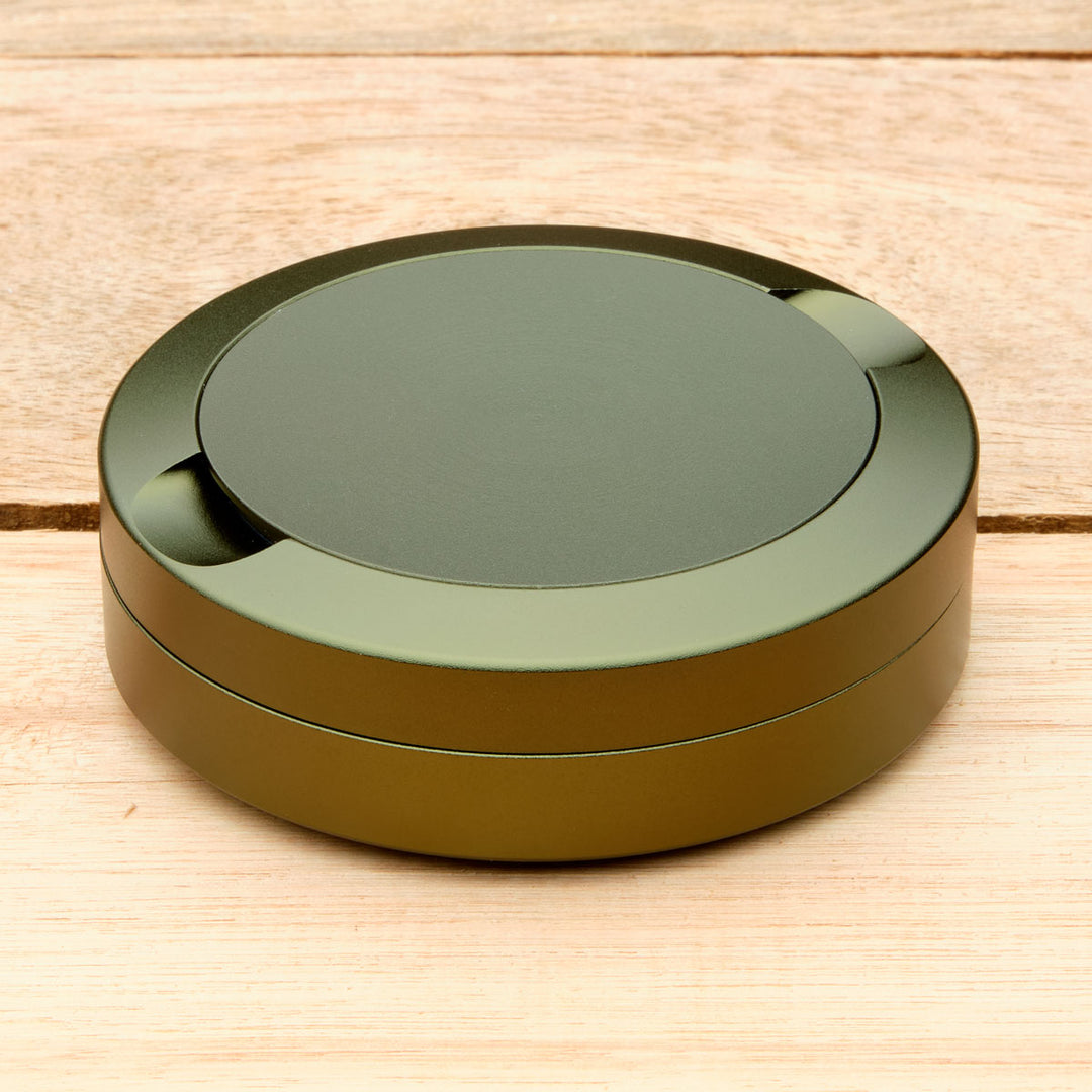 Round green aluminum pouch case on a wooden surface