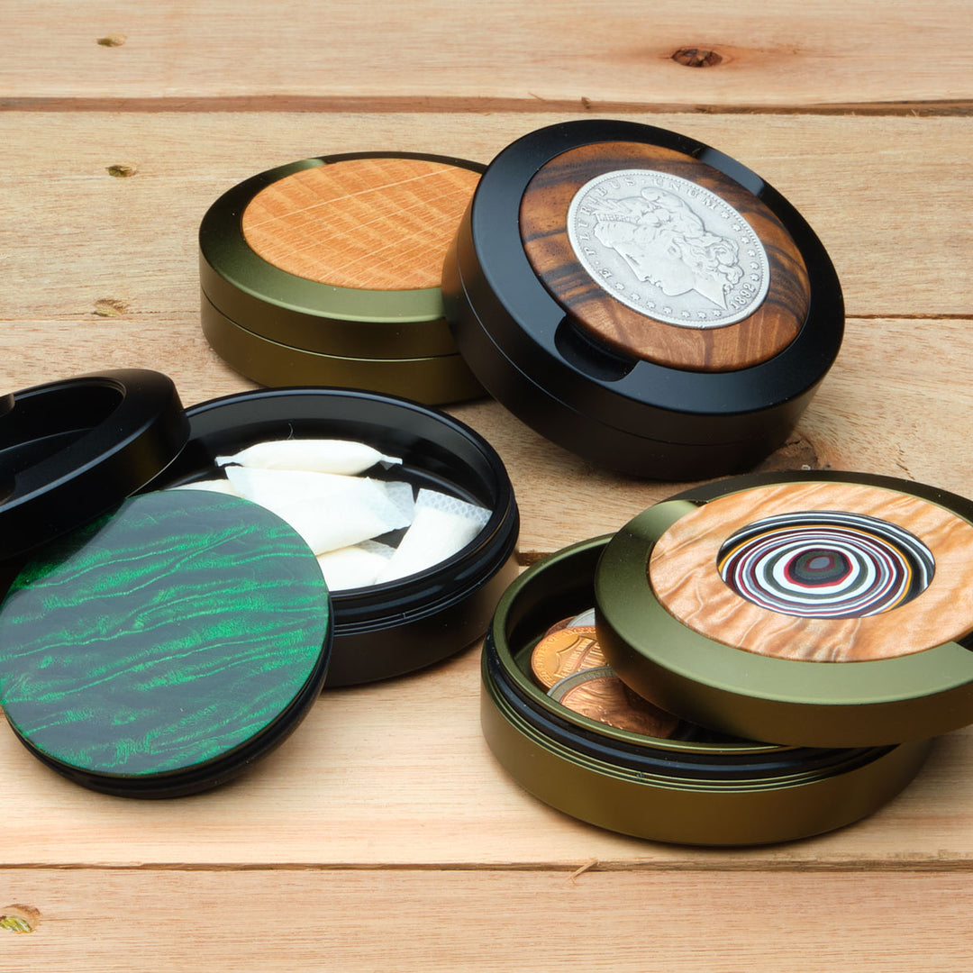 Collection of aluminum pouch cases with various designs on a wooden surface