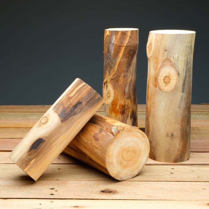 Three wooden logs of different sizes on a wooden surface with a dark background