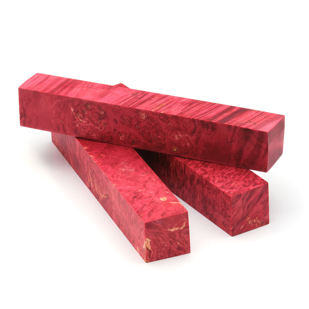 Three red dyed box elder burl pen blanks laying on a white background