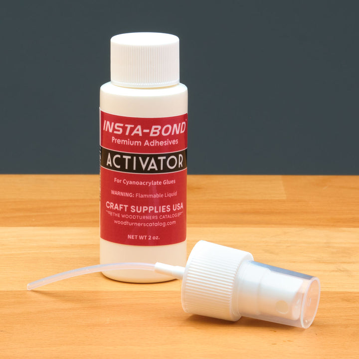 Insta-Bond activator bottle with a pump spray nozzle on a wooden surface