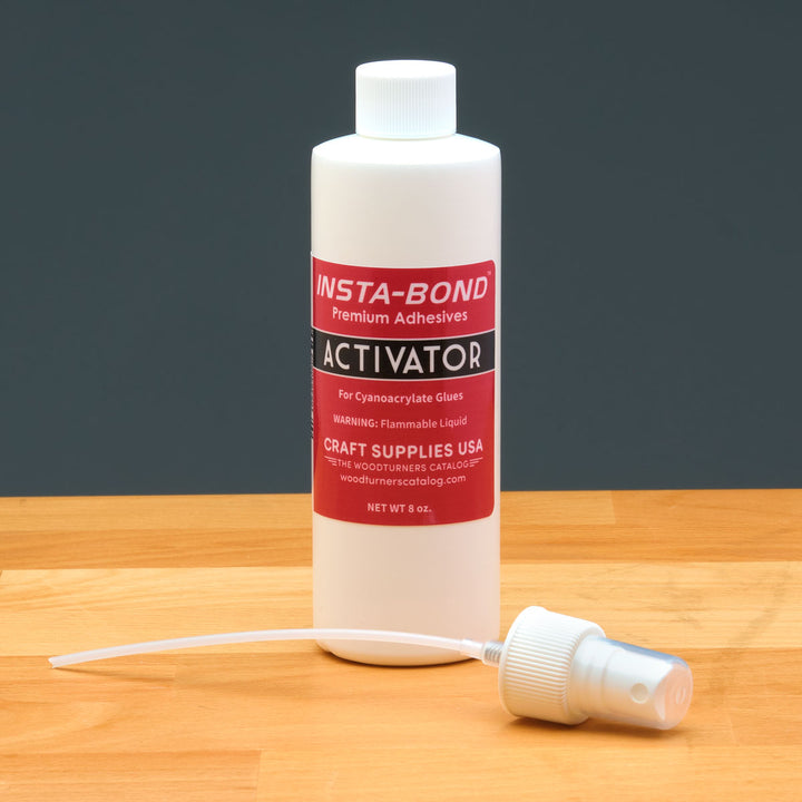 Insta-Bond activator bottle with pump spray nozzle on a wooden surface