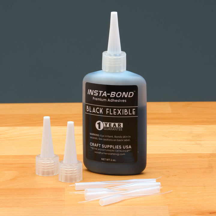 Insta-Bond black flexible adhesive bottle with applicators on a wooden surface