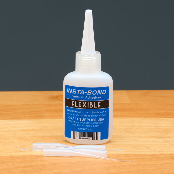 Insta-Bond adhesive bottle with applicators on a wooden surface