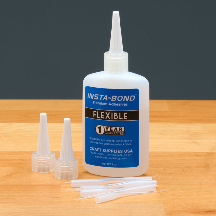 Insta-Bond flexible adhesive bottle with applicators on a wooden surface