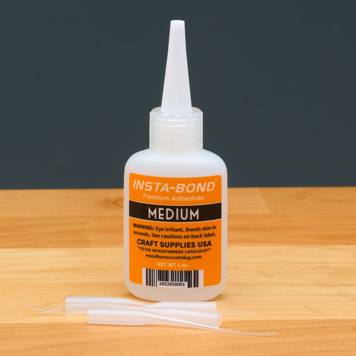 Insta-Bond adhesive bottle on a wooden surface with a dark background