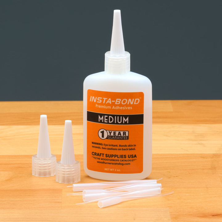 Insta-Bond medium glue bottle with applicators on a wooden surface