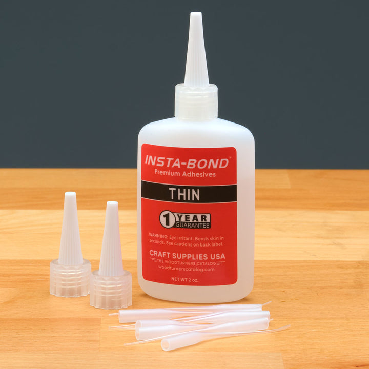 Insta-Bond Thin glue bottle with applicators on a wooden surface